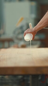 Carpenter pouring white glue onto wood board