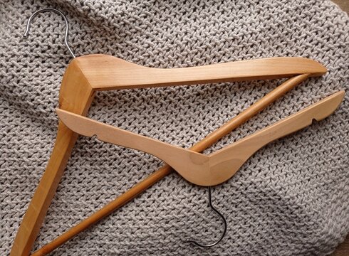 Top view of wooden clothes hangers of various sizes on a gray blanket.