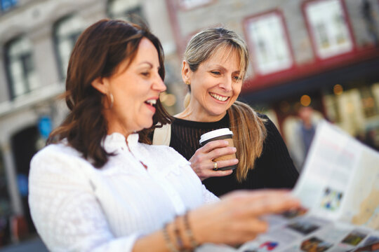 Beautiful senior women outdoors in the city. friends having fun, shopping and bonding looking city map