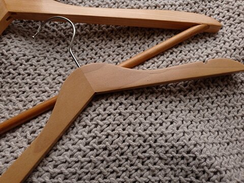 Close up of wooden clothes hangers of various sizes on a gray blanket.