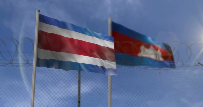 Cambodia and Thailand waving flags on country border concept. Cambodian and Thai blowing banner with barbed wire frontier fence.