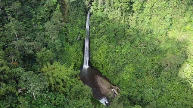 Wide aerial drone hover showcasing the entire Munduk Waterfall in lush jungle setting, Bali, Indonesia.
