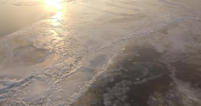 Large frozen river at sunset, view from the sky, flight over the frozen river