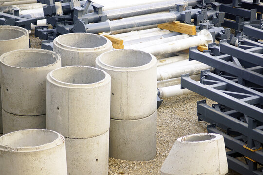 Grouped cylindrical concrete well units positioned near structural elements inside open-air construction zone. Illustrates municipal service component availability and underground engineering hardware