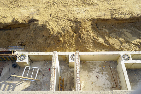 Top view of concrete foundation cells with rebar column starters and anchor bolt pedestals. Demonstrates structural grid layout, reinforced concrete coordination, and substructure framing preparation.