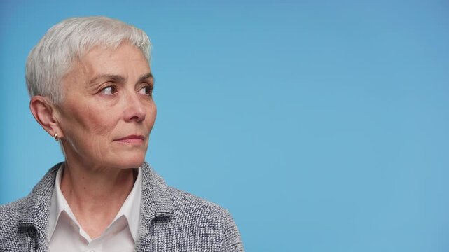 Senior woman looking at copy space isolated on blue