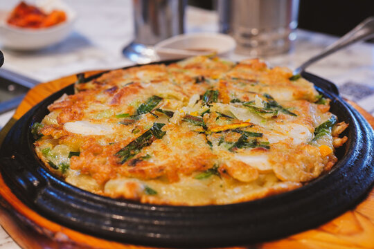 Freshly cooked crispy Korean Pajeon pancake served on a sizzler platter at a Korean restaurant