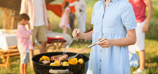 Happy woman cooking food at barbecue party on summer day