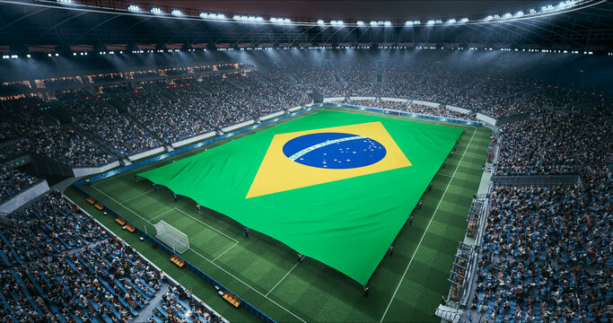 Professional Stadium Soccer Game Championship With Flag of Brazil Spread Across the Pitch Before Football Match Start. Cheering Crowds of Fans Surround the Field. Aerial Wide Shot