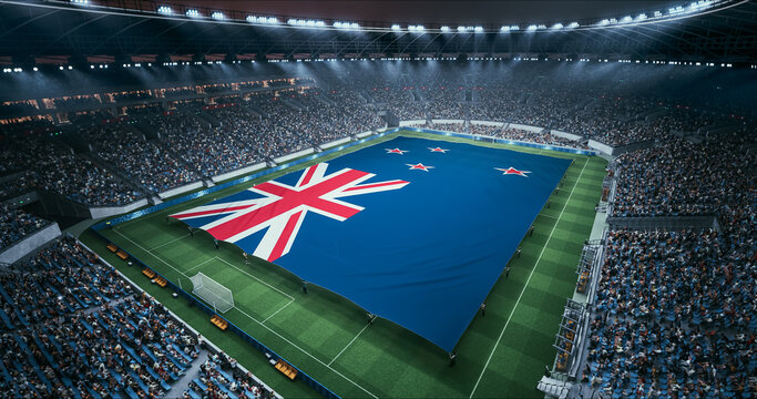 Professional Stadium Soccer Game Championship With Flag of New Zealand Spread Across the Pitch Before Football Match Start. Cheering Crowds of Fans Surround the Field. Aerial Wide Shot
