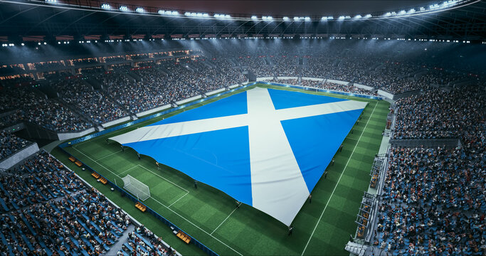 Professional Stadium Soccer Game Championship With Flag of Scotland Spread Across the Pitch Before Football Match Start. Cheering Crowds of Fans Surround the Field. Aerial Wide Shot