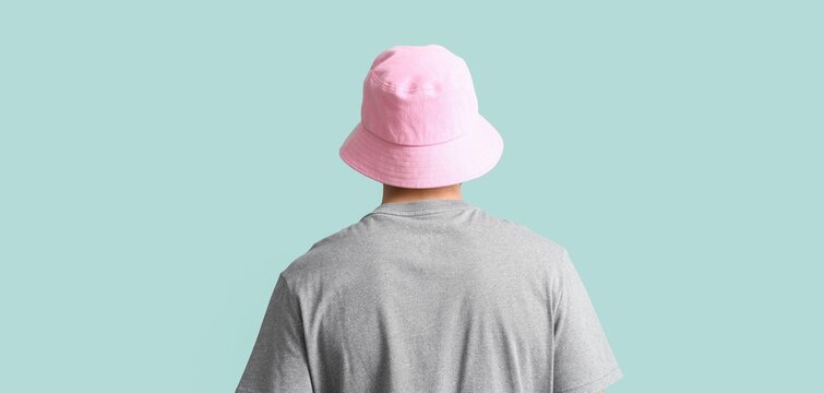 Young man in stylish bucket hat on grey background, back view