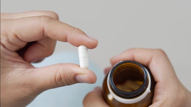 close up woman hand holding a medicine, with pours the pills out of the yellow orange medicine bottle. Stop drug use Taking Medication Caring for the health care medical concept.