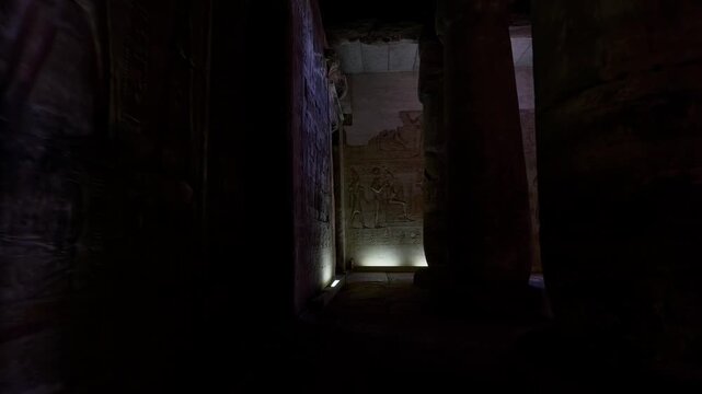 Sacred hypostyle hall at Abydos temple of Seti I, Egypt, ancient columns with carved hieroglyphics and gods receding in atmospheric perspective toward illuminated sanctuary.
