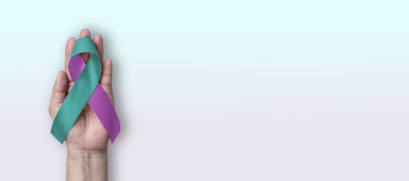 Teal purple ribbon awareness for Sexual Assault, Domestic Violence, World Suicide Prevention Day, trauma and abuse awareness ribbon color on hand support copy space background