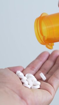 close up woman hand holding a medicine, with pours the pills out of the yellow orange medicine bottle. Stop drug use Taking Medication Caring for the health care medical concept.