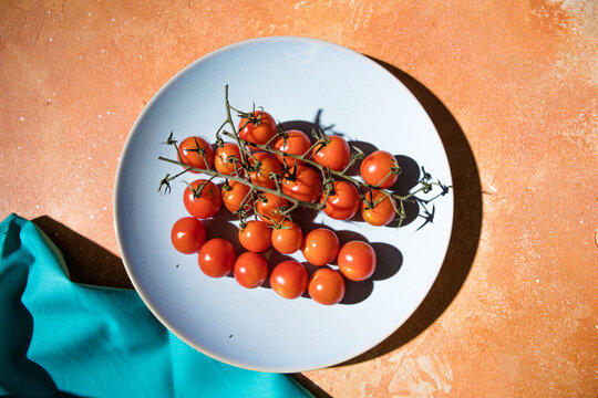 Tiny cherry tomatoes ciliegini, pachino, cocktail. group of cherry tomatoes on a color concrete background.