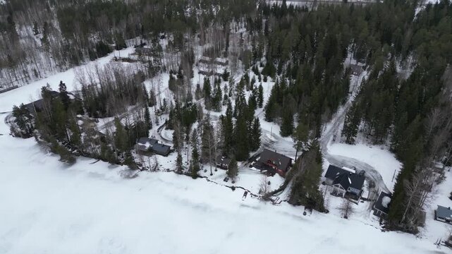 Aerial drone view of Ruka Kuusamo region Northern Ostrobothnia Finland with lakeside cabins, frozen lake and snow covered forest creating cold winter landscape