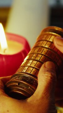 Macro shot of thumbs rotating cryptex letters in warm candlelight, highlighting tension, focus, and the act of decoding hidden secrets. Ideal for escape room and game concepts