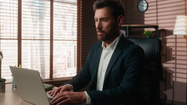 Focused Caucasian business man typing laptop working with corporate software at office table 40s businessman male executive work with computer technology agent serious browsing internet in company