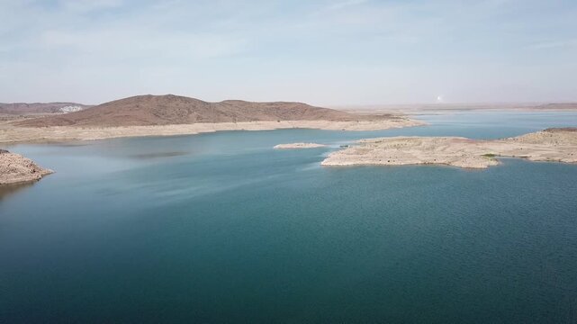 Drone footage showing the visible marks of water depletion on rocky hillsides at a Moroccan reservoir, illustrating severe drought and environmental change.