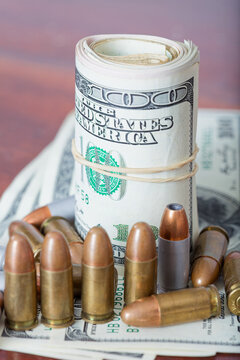 Rolled US Dollar Bill with Upright and Scattered Pistol Ammunition brass and silver casings