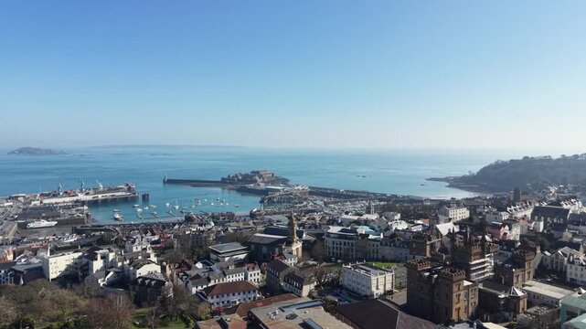 St Peter Port Guernsey,high circling footage  of St James Assembly hall and Elizabeth College with views across the town,harbour ,Castle Cornet,Havelet Bay to Herm Jethou and Sark in bright sun