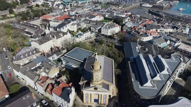 St Peter Port Guernsey,aerial detailed view of St James Assembly hall and The Royal Court starting with views across the town,harbour and to Herm and ending with direct overhead shot in bright sun