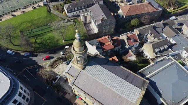 St Peter Port Guernsey,reveal of St James Assembly hall and Elizabeth College starting overhead revealing views of the college and across the town in late afternoon sun