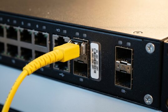 Yellow fiber patch cable plugged into network switch port bank