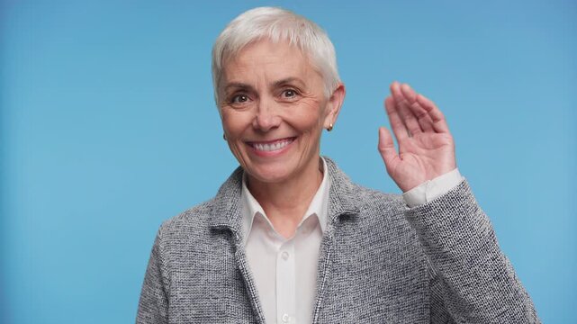 Senior woman waving hello gesture on blue background