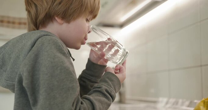 Kid Boy Drinks Glass of Water in Kitchen. 4K 10-bit
