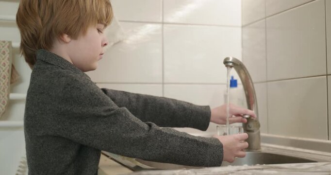 Kid Boy Drinks Glass of Water in Kitchen. 4K 10-bit