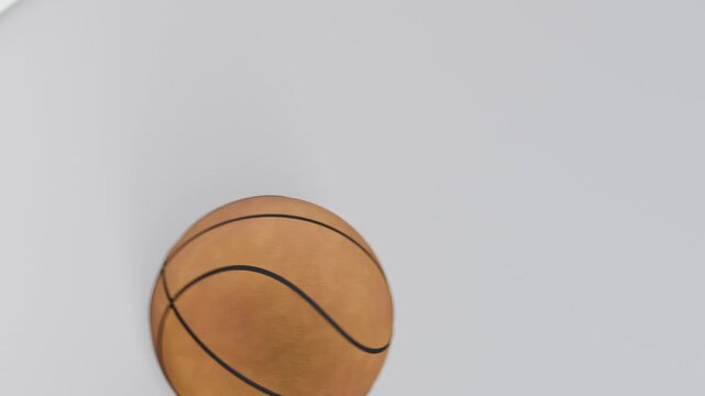 Appearing above cutout, orange basketball dropping through glossy white panel, settling to center