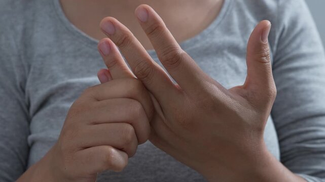 pain in hands and joints. woman feeling hand discomfort, rubbing and massaging wrist and fingers, performing warm-up exercises to alleviate pain, carpal tunnel syndrome, arthritis, or cramp symptoms.