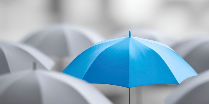 a blue umbrella stands out from the crowd of gray umbrellas, symbolizing difference and individuality in an urban setting.