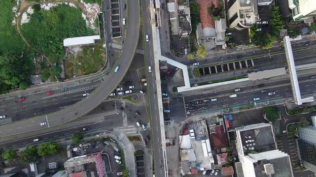 Jakarta, Indonesia - April 26th 2026: Aerial View of Busy City Intersection with Traditional Minangkabau Roof Architecture and Modern Skyscrapers. Urban Infrastructure under Hazy Overcast Sky