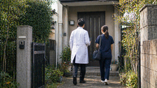 Doctor and nurse walking toward a Japanese home for a medical visit