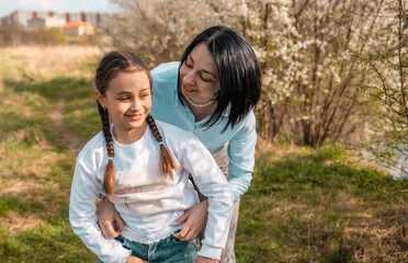 Naklejka premium Loving mother hugging her little daughter in the park while looking away together at the view