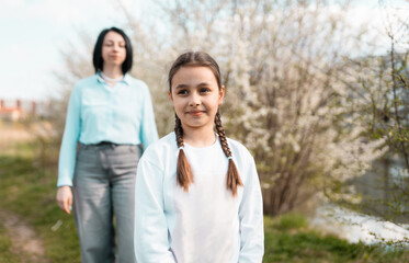 Obraz premium Little girl in focus waiting for her mother walking towards her in the blurred background in the park
