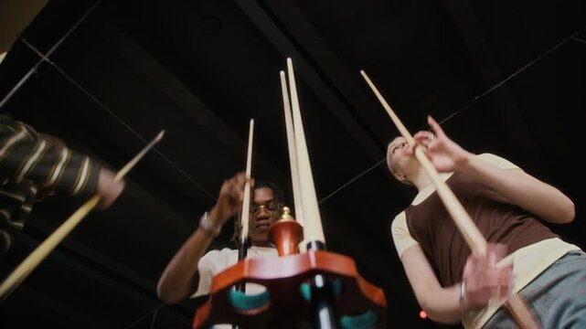 Low angle shot of three young adult friends grabbing cues from rack while starting match in billiards game during casual gathering at pool hall