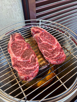Due fette di ribeye di wagyu uruguaiano in cottura su un barbecue casalingo