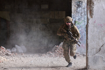Obraz premium Armed Soldier In Camouflage Tactical Gear Running Through Urban Ruins With Rifle Ready