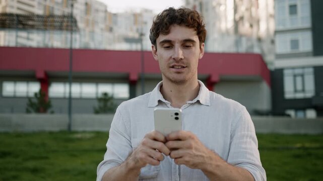 Happy smiling Caucasian business man holding mobile phone looking in smartphone joyful businessman smile enjoy good news message web net scrolling male guy developer using cellphone in city downtown