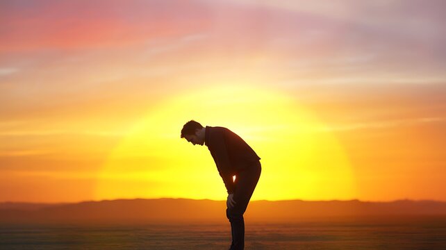 Man bending over with hands on knees against a vibrant sunset sky