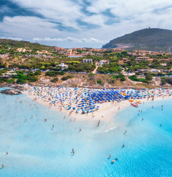 Aerial view of famous La Pelosa beach at sunny summer day. Stintino, Sardinia island, Italy. Top drone view of sandy beach, swimming people, clear blue sea, sky with clouds. Tropical seascape