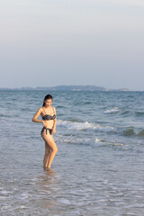 Fototapeta premium Drone view of a woman in a black bikini relaxing happily on a sandy beach.
