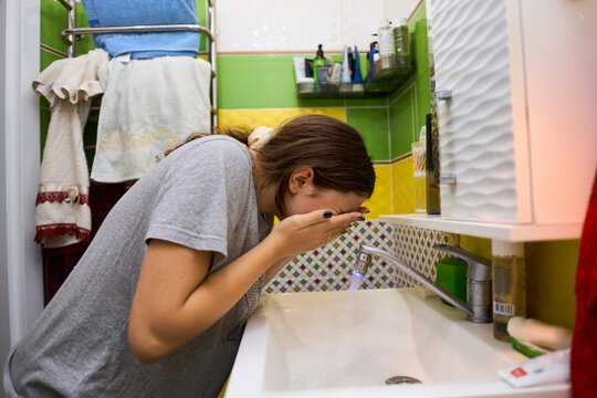 Teen girl washing face in bathroom