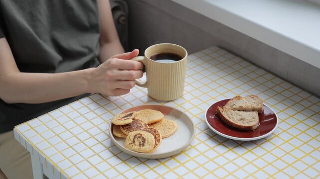 woman eats flatbread pancakes, drinks coffee. vegetarian diet for body health, cooking. person eats breakfast or lunch in the kitchen. delicious and healthy food cooked at home. high quality 4k video