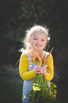 Young girl holding freshly harvested garden vegetables